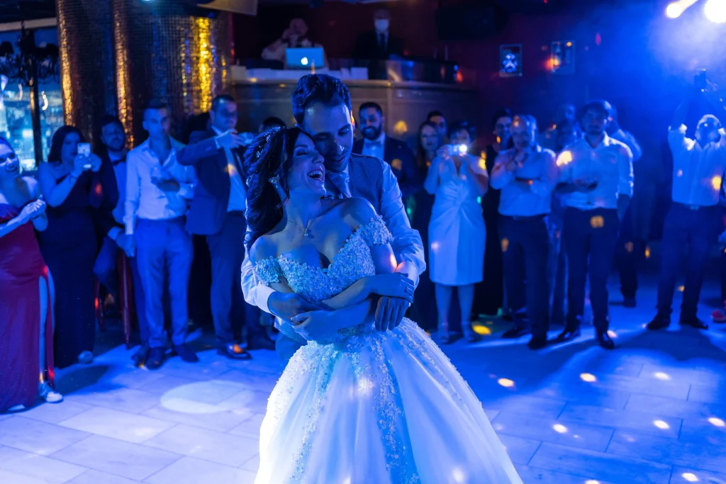 una pareja de novios bailando en una pista durante una boda con luces azules