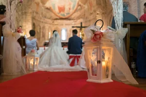 pareja de novios frente a un altar de una iglesia con un farolillo en primer plano