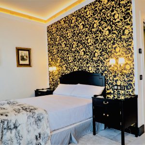 habitación con cama de matrimonio, pared decorada con filigrana dorada y negra