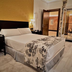 habitación con cama de matrimonio decorada con estilo versace dorado